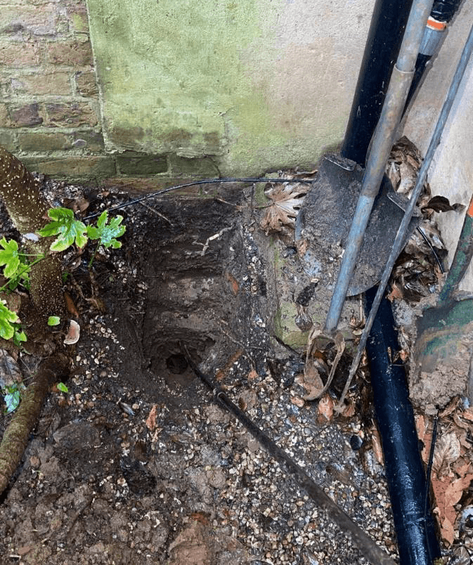 Excavation against the wall with the service pipe exposed