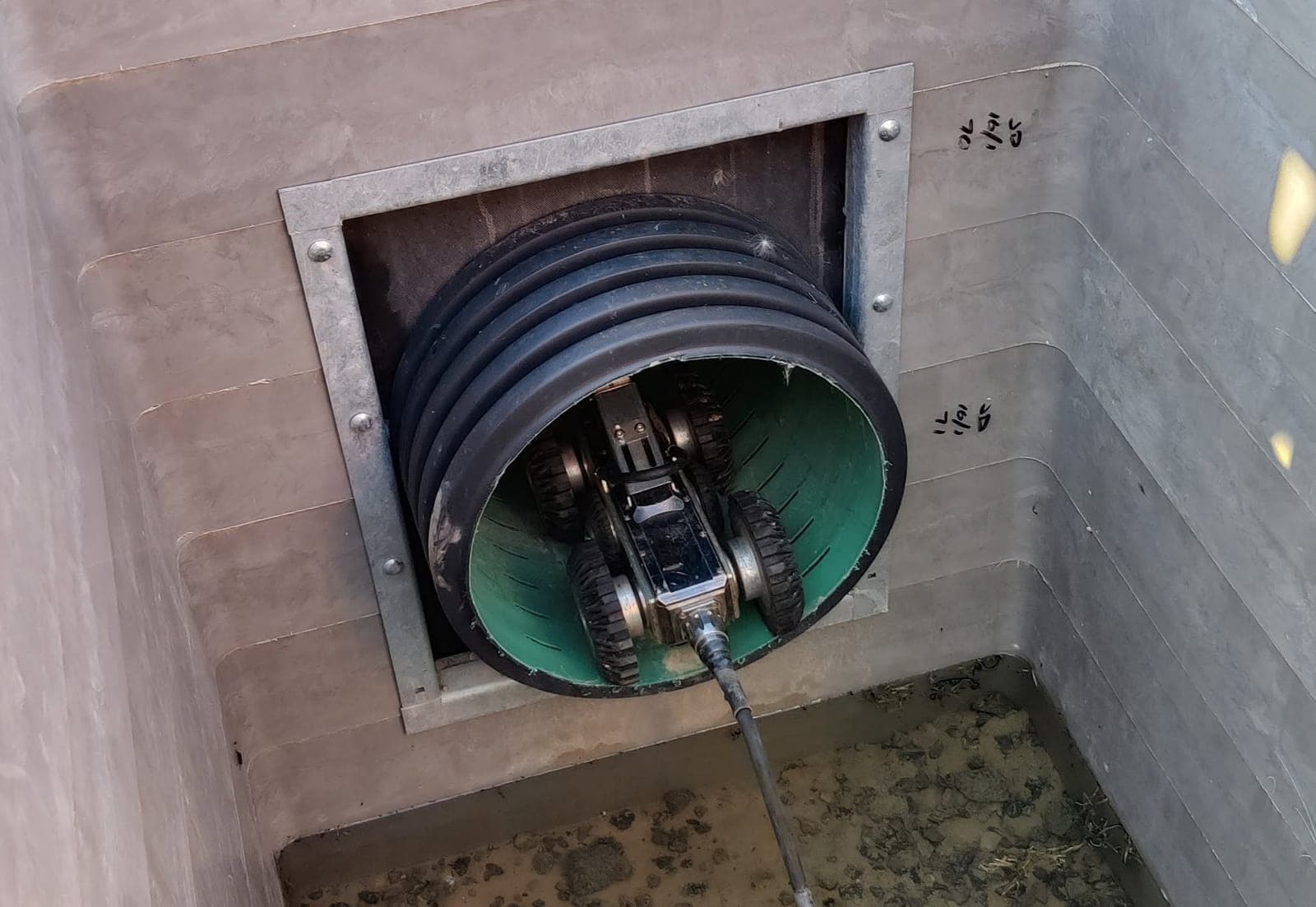 Robotic crawler CCTV unit entering a large-diameter twin-wall main from inside a new chamber