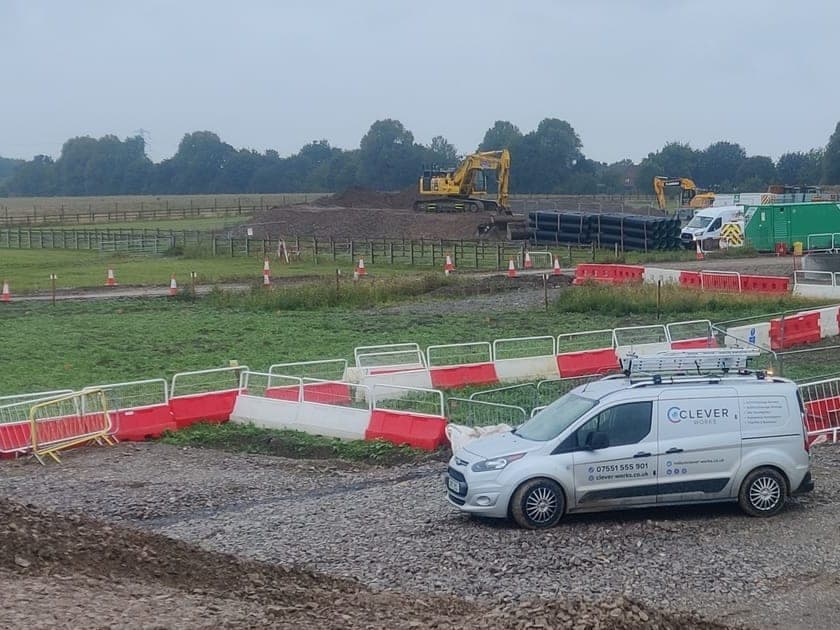 Clever Works survey van on a live infrastructure construction site with large-diameter pipe stacks and excavators